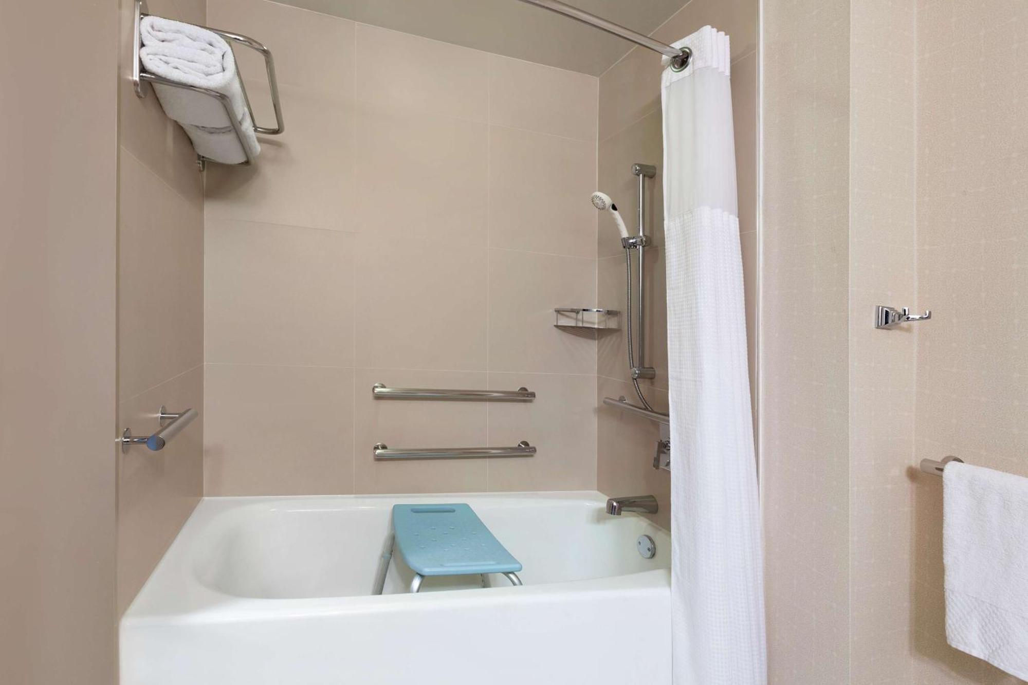 Habitación con cama extragrande, bañera adaptada para personas con movilidad reducida y vistas a la ciudad